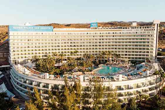 Hotelbygning med pool og omgivelser af grønne områder. (AI-genereret tekst)