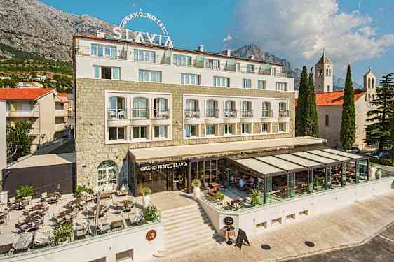 Billede af Grand Hotel Slavia med udendørsterrasse og glaseret restaurantområde. (AI-genereret tekst)