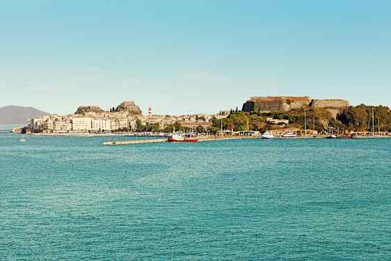 En by ved havet med historiske bygninger og en fæstning på en bakke. (AI-genereret tekst)