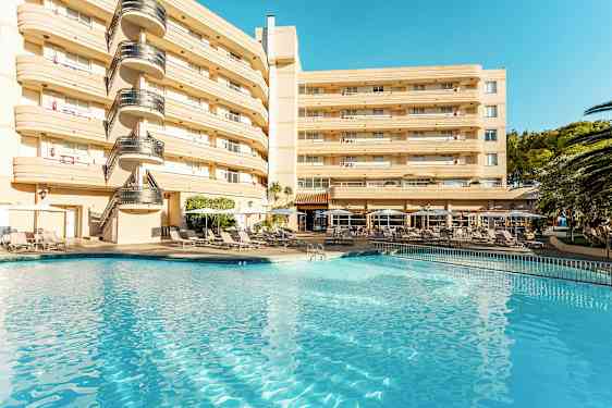 Hotelbygning ved en pool med liggestole og parasoller. (AI-genereret tekst)