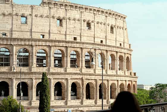 Billede af Colosseum i Rom, Italien, med en kvinde i forgrunden. (AI-genereret tekst)