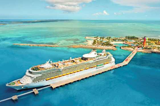 Et krydstogtskib ligger ved en kaj i en tropisk miljø med turkis vand og øer i baggrunden. (AI-genereret tekst)