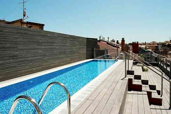 En tagterrasse med en lang pool omgivet af terrassebrædder og nogle siddepladser på siden. (AI-genereret tekst)