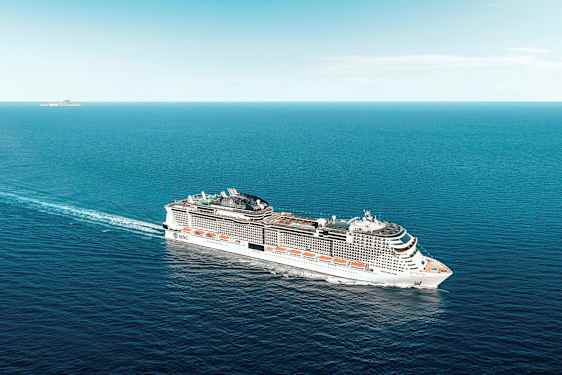 Et stort krydstogtskib sejler over havet under en klar himmel. (AI-genereret tekst)