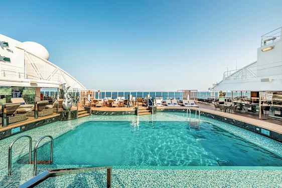 En pool på krydstogtskibets dæk med liggestole og havudsigt. (AI-genereret tekst)