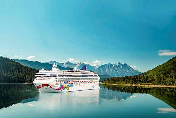 Krydstogtskib på en sø med bjerge og skov i baggrunden. (AI-genereret tekst)