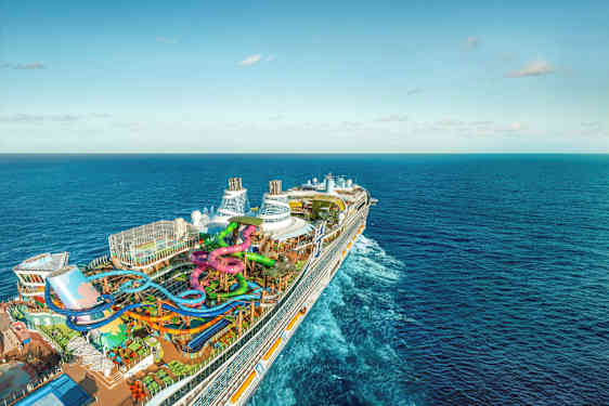 Et stort krydstogtskib med vandrutsjebaner og swimmingpools på dækket, omgivet af hav (AI-genereret tekst)