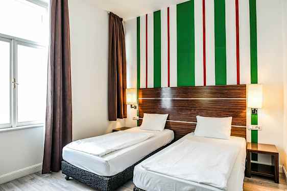 Hotelværelse med to enkeltsenge, moderne indrettet i lyse farver og med stribet vægdekoration. (AI-genereret tekst)