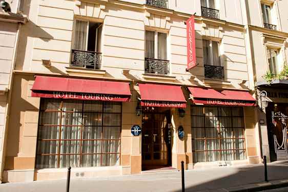 Facaden på Hotel Touring med røde markiser og indgang med glasdøre. (AI-genereret tekst)
