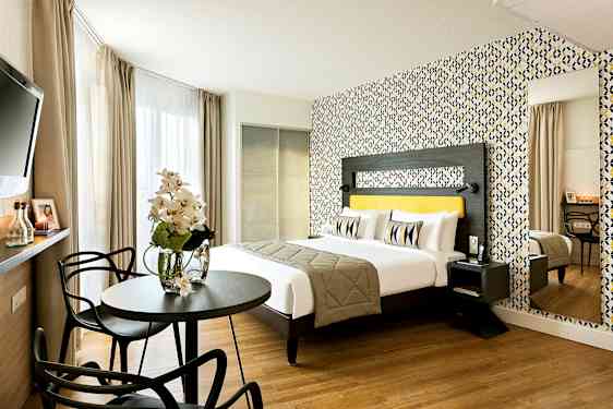 Et moderne hotelværelse med en dobbeltseng, farverigt tapet og siddeområde. (AI-genereret tekst)