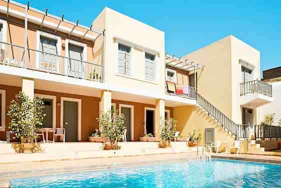 Billede af en bygning med altaner og en swimmingpool i forgrunden. (AI-genereret tekst)