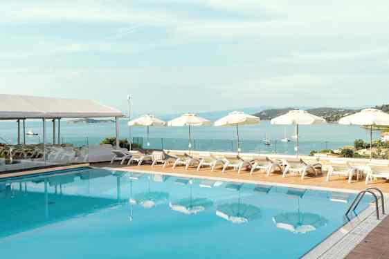 En pool med liggestole og parasoller ved havet. (AI-genereret tekst)