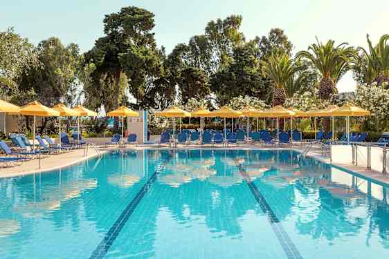 Udendørs swimmingpool med blåt vand, omgivet af liggestole, parasoller og grønne træer. (AI-genereret tekst)