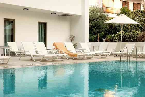 Udendørs pool med liggestole og parasol. (AI-genereret tekst)