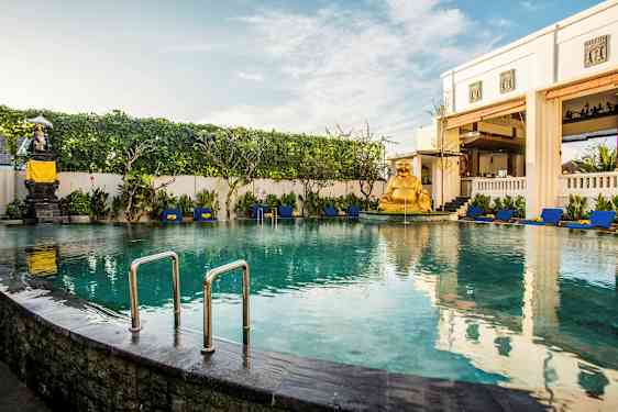 En indbydende pool omgivet af liggestole og grønne omgivelser, med en gylden statue som dekoration. (AI-genereret tekst)