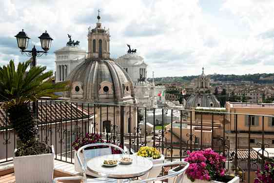 Billede af en terrasse med udsigt over Roms arkitektur, herunder kupler og monumenter. (AI-genereret tekst)