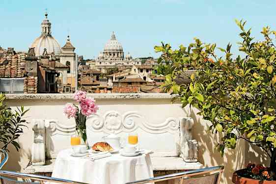 En terrasse med et bord dækket til morgenmad og udsigt over byens tage og en katedral. (AI-genereret tekst)