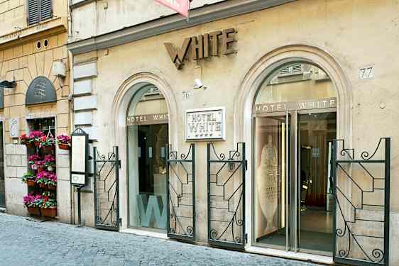 Indgangen til Hotel White, en bygning med to glasdøre og dekoreret facade. (AI-genereret tekst)