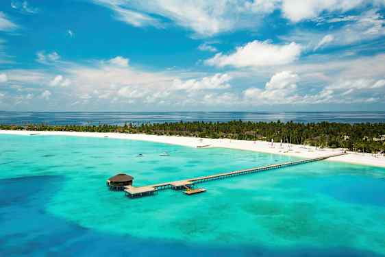 Luftfoto af en tropisk strand med en mole, der strækker sig ud i det turkise vand. (AI-genereret tekst)