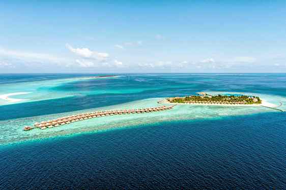 Luftfoto af en tropisk ø og villaer på pæle i klart blåt hav. (AI-genereret tekst)