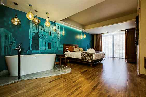 Et hotelværelse med en seng, et fritstående badekar og blå væggmalerier. (AI-genereret tekst)