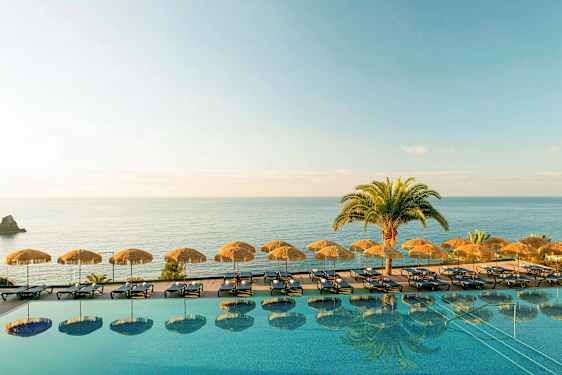 En infinitypool med liggestole og parasoller ved havet. (AI-genereret tekst)