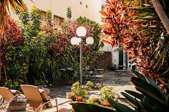 En solrig gårdsplads med havemøbler og beplantning. (AI-genereret tekst)