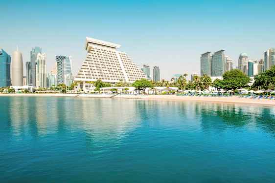 Billede af en by med moderne arkitektur ved en rolig strand og vand. (AI-genereret tekst)