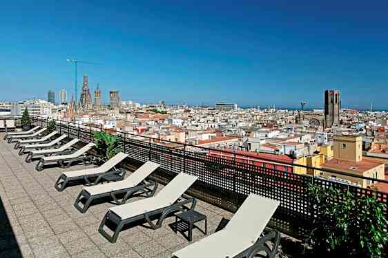 En tagterrasse med liggestole og udsigt over en by med kirke og blå himmel. (AI-genereret tekst)