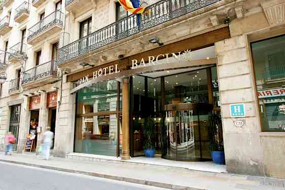 Et hotel med en glasindgang og dekorativt skilt ovenover, beliggende ved en gade med fortov. (AI-genereret tekst)