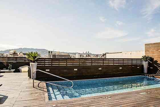 En tagterrasse med en pool, omgivet af træpaneler og med udsigt over en by. (AI-genereret tekst)