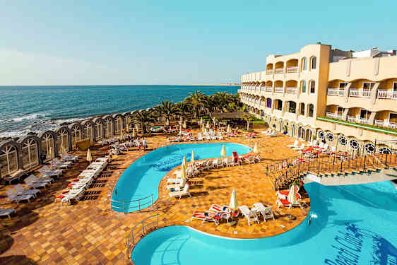 Hotelområde med pool og havudsigt. (AI-genereret tekst)