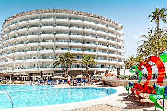 Hotelbygning med altaner, palmer og poolområde. (AI-genereret tekst)