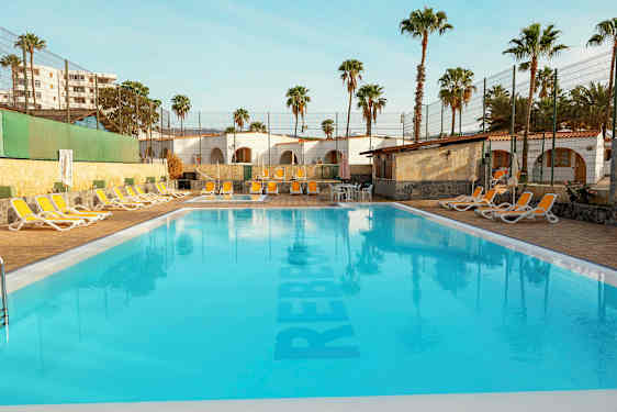 Udendørs pool med liggestole og palmer i baggrunden. (AI-genereret tekst)