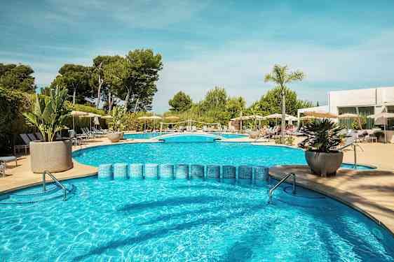 Udendørs swimmingpool med liggestole og parasoller samt omgivende grønne områder. (AI-genereret tekst)