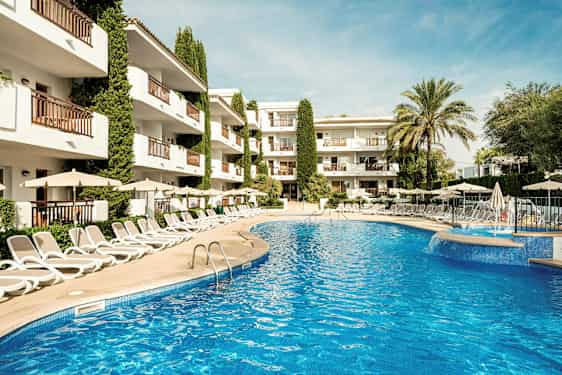 Billede af en udendørs pool omgivet af liggestole og parasoller, med et hotel i baggrunden. (AI-genereret tekst)