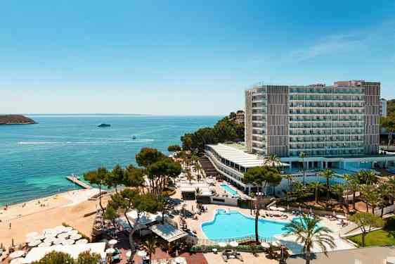 Luftfoto af et hotelkompleks ved havet med swimmingpools, grønne områder og en strand. (AI-genereret tekst)