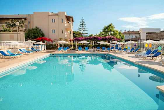 En udendørs pool omgivet af liggestole og parasoller ved et hotel. (AI-genereret tekst)