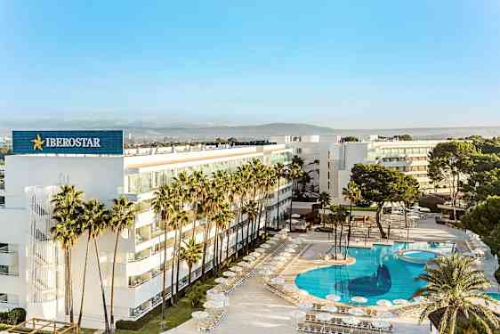 Et moderne hotel omgivet af palmer med en stor, klarblå pool. (AI-genereret tekst)