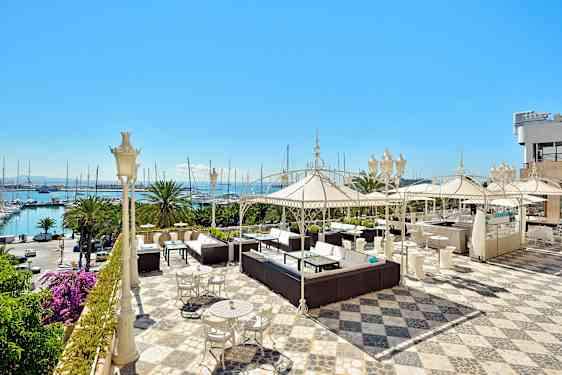 En rummelig terrasse med siddeområder, parasoller og havudsigt. (AI-genereret tekst)