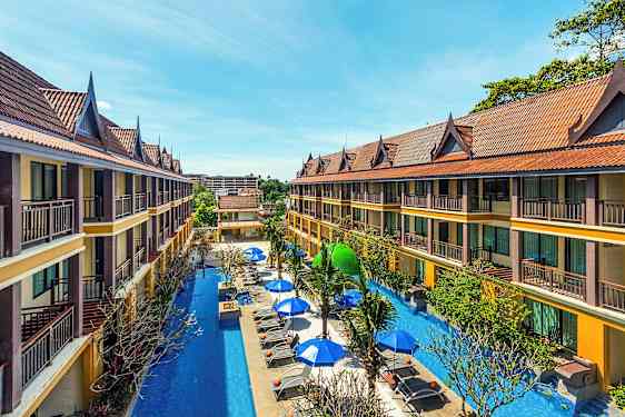 Toetagers hotelbygninger med skrånende tage omgiver en pool med liggestole og parasoller. (AI-genereret tekst)