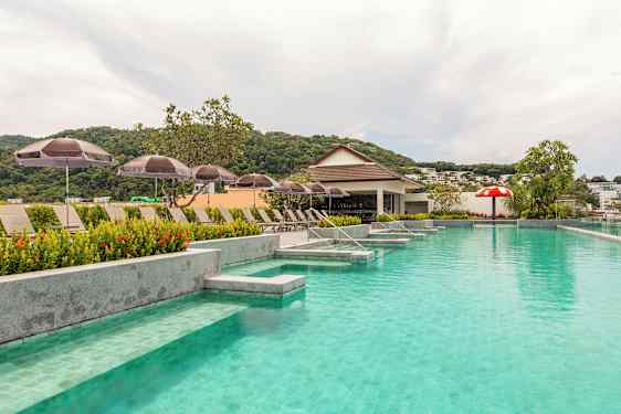 Poolområde med liggestole og parasoller og en lille bar i baggrunden. (AI-genereret tekst)