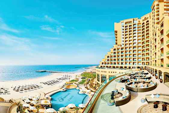 Et hotel beliggende ved strandkanten med pool og liggestole på stranden. (AI-genereret tekst)