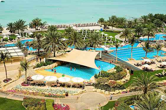 Et feriested med poolområde tæt på stranden, omgivet af palmer og liggestole. (AI-genereret tekst)