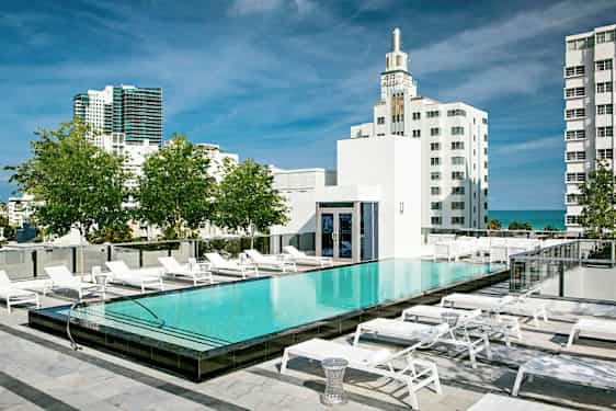 En tagpool med liggestole omkring, omgivet af moderne bygninger og grønne områder. (AI-genereret tekst)