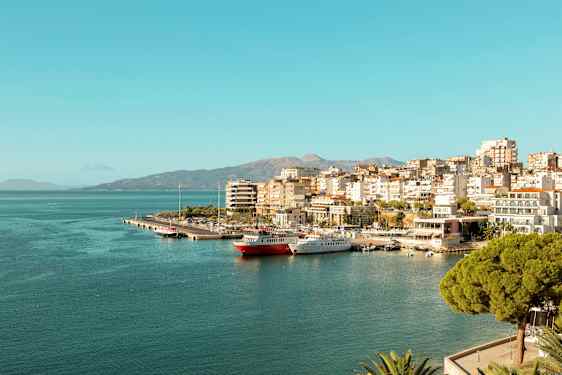 Udsigt over en by ved havet med småbådshavn og bygninger langs kysten. (AI-genereret tekst)