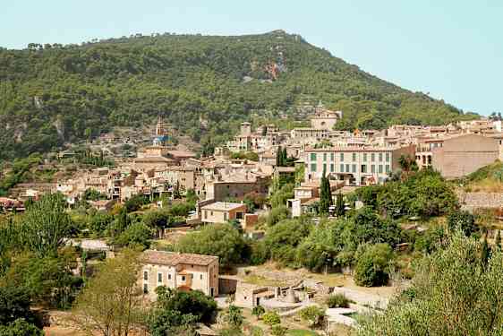 Billede af en bjerglandsby med flere stenhuse omgivet af frodig vegetation. (AI-genereret tekst)