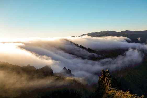 Skyer driver hen over en bjergkæde ved solopgang eller solnedgang. (AI-genereret tekst)