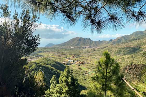 Udsigt over et grønt dalområde med landsbyer og bjerge i baggrunden. (AI-genereret tekst)