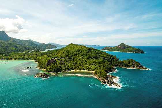 Luftfoto af en frodig ø omgivet af klart blåt hav og mindre øer i baggrunden. (AI-genereret tekst)